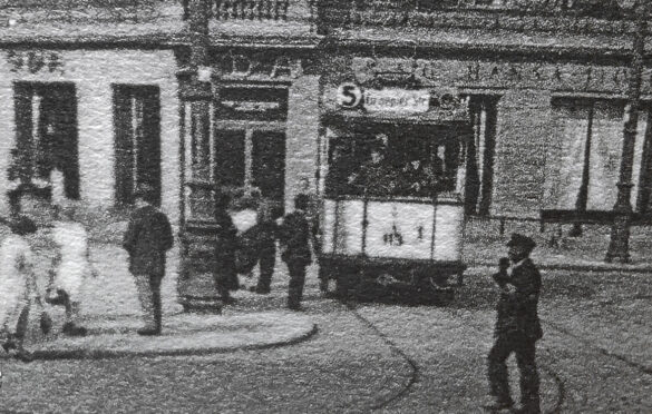 Zbliżenie na tramwaj linii 5 jadący od wschodniej strony Bramy Królewskiej, wejście frontowe narożnej kamienicy w tle