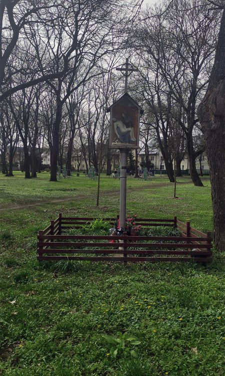 Krzyż z umieszczoną Pietą na terenie parku, a dawnego cmentarza